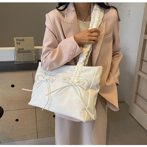 Detailopname van witte nylon schoudertas met decoratieve strikken en geplooide schouderband