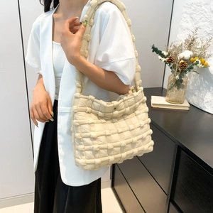 Detail shot of beige quilted puffer shoulder bag showing soft texture and woven pattern