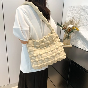 Close-up of cream woven quilted tote bag showing puffy texture and thick shoulder strap