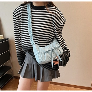 Detail of light blue pleated canvas crossbody bag featuring a decorative bow knot