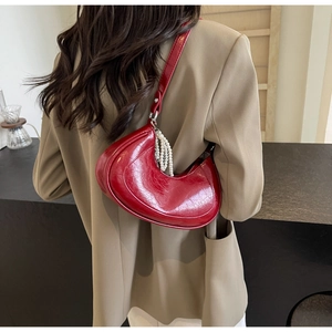Detail view of dark red half-moon shoulder bag with elegant white pearl tassels