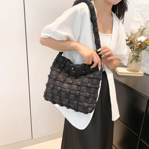 Detailed view of black woven quilted puff shoulder bag with soft padded texture