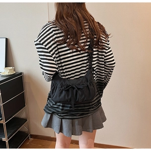 Detail of black pleated crossbody bag with ribbon bow and textured shoulder strap