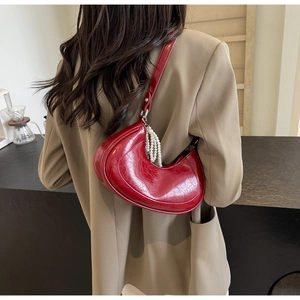 Close-up of a dark red hobo bag with glossy leather texture and elegant pearl charm detail