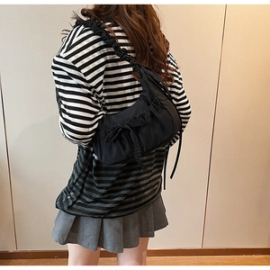 Close-up of black ruched canvas shoulder bag featuring bow detail and ruffled strap