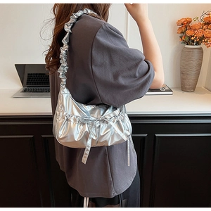 Close-up of silver metallic crossbody bag with ruffled strap and bow details