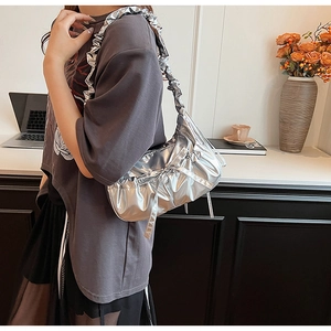 Close-up of a silver pleated canvas crossbody bag with decorative bow and metallic finish