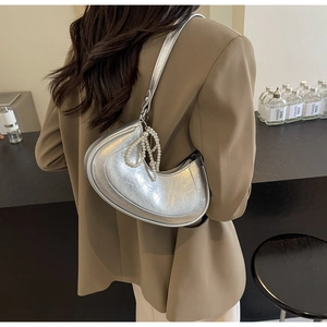 Detail of silver metallic crescent bag featuring elegant pearl chain and textured leather