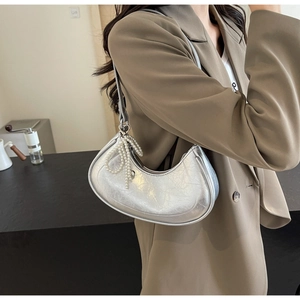 Detailed shot of silver crescent bag with pearly bow pendant on model in blazer