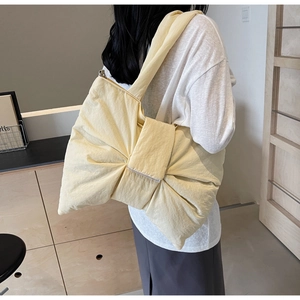 Detail of light yellow oversized bow shoulder bag with pleated fabric and wide strap