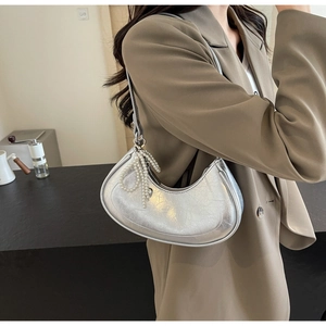 Detail of silver crescent bag featuring metallic pleated texture and pearl bow charm