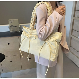Detail van de geplooide schouderband en strik op een gele nylon schoudertas