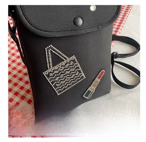 Detail of black crossbody phone bag featuring rhinestone lipstick and tote bag patterns