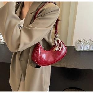 Detail of dark red crescent shoulder bag with glossy leather and pearl chain strap