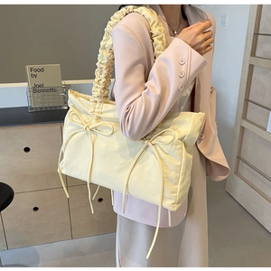 Detail van een lichtgele shopper met geplooide banden en delicate strikversieringen