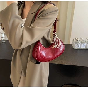 Detail of red crescent bag with glossy patent leather and double-layered pearl chain