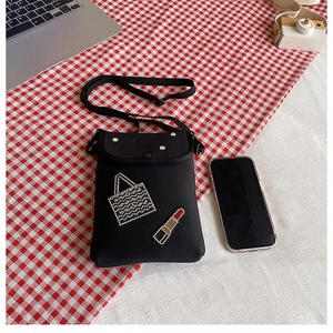 Detail of black crossbody phone bag with rhinestone lipstick and handbag patterns