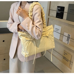 Detail van een crèmebeige geplooide shopper met strikjes gedragen op een roze blazer