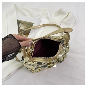 Detailed view of gold sequin handbag with zipper closure and burgundy lining