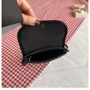 Detail of black canvas messenger bag featuring a secure magnetic snap closure