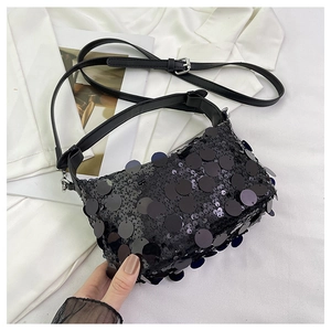 Close-up of black sequin handbag featuring large round sequins and metal buckle