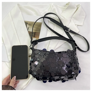 Detail of black sequined handbag with adjustable leather strap and silver buckle