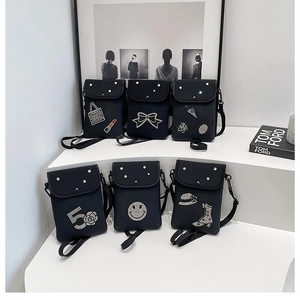 Detail view of small black crossbody bags with various sequin and rhinestone patches