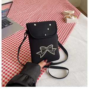Detail of black crossbody phone bag with sparkling rhinestone bow and silver studs