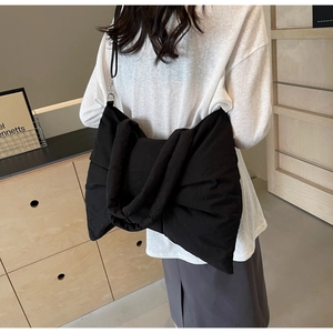 Rear view of model wearing a stylish large black puffy bow tote bag with adjustable strap