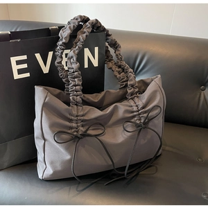 Detailopname van antracietkleurige nylon tas met gerimpelde handvatten en zwarte strikken