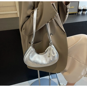 Detail of silver metallic hobo bag featuring pearl bow charm and heart-shaped zipper