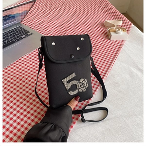 Detail of black crossbody mini bag featuring rhinestone number 5 and camellia flower