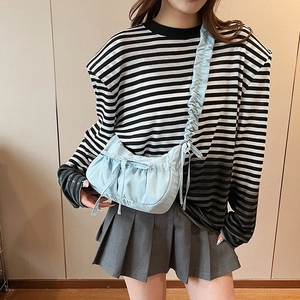 Light blue ruched dumpling crossbody bag with bow details worn by a model in casual style