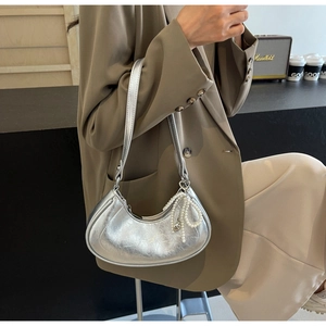 Detailed shot of silver crackle leather moon bag with a pearl bow charm and slim strap