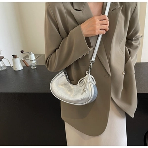 Detailed shot of silver textured dumpling bag with pearl bow charm and metal finish