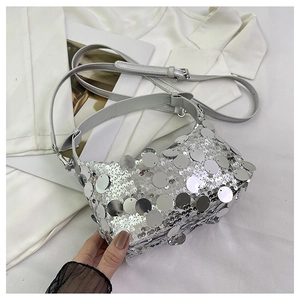 Detail of silver sequin crossbody bag texture placed on white silk fabric for party look