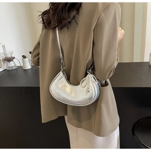 Detail view of silver moon crescent bag with pearl bow charm and pleated texture