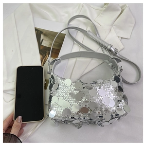 Detail of silver sequin handbag with adjustable strap next to a mobile phone for size comparison