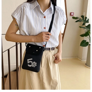Detailed shot of the black canvas mini crossbody bag featuring camellia and number 5