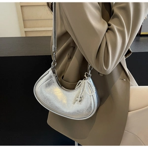 Silver metallic crackle leather crescent bag with pearl charm detail on a brown blazer