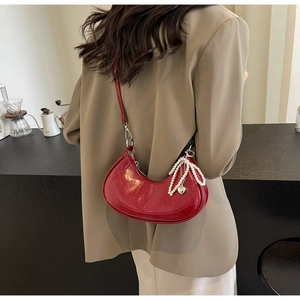 Red glossy half-moon underarm bag featuring pearl tassel and heart charm details