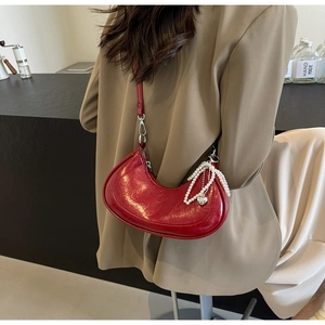 Detail of red crescent bag with pearl and heart charms on textured faux leather