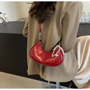Detail of red crescent leather bag with pearls and a silver heart pendant accessory