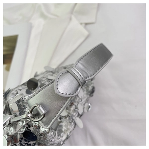 Close-up of sparkling silver sequins and metal buckle detail on the stylish handbag