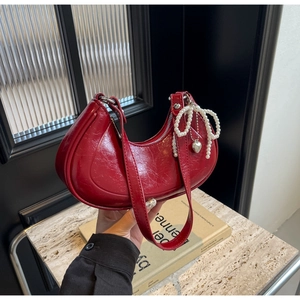 Detail of red wrinkled patent leather hobo bag with pearl bow and silver heart charm