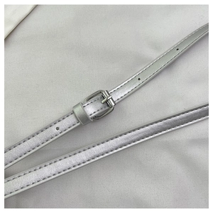 Detailed shot of silver sequin handbag shoulder strap with metal buckle and stitching