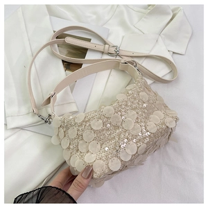 Close-up of cream sequin handbag showing round glitter texture and silver buckle detail