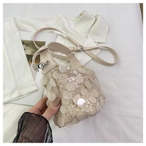 Detailed top view of cream sequin bucket bag with silver metal buckle and slim strap