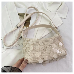 Macro shot of beige sequin handbag detailing with large translucent paillettes and hardware