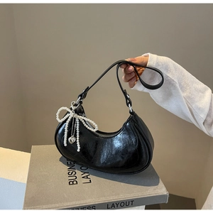 Detail of black crescent hobo bag in glossy pleated leather with pearl bow charm